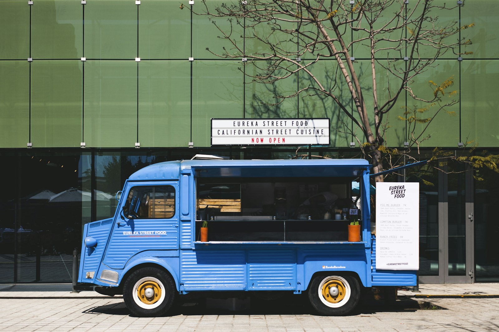 A colorful blue food truck with its service window open, parked on a city street